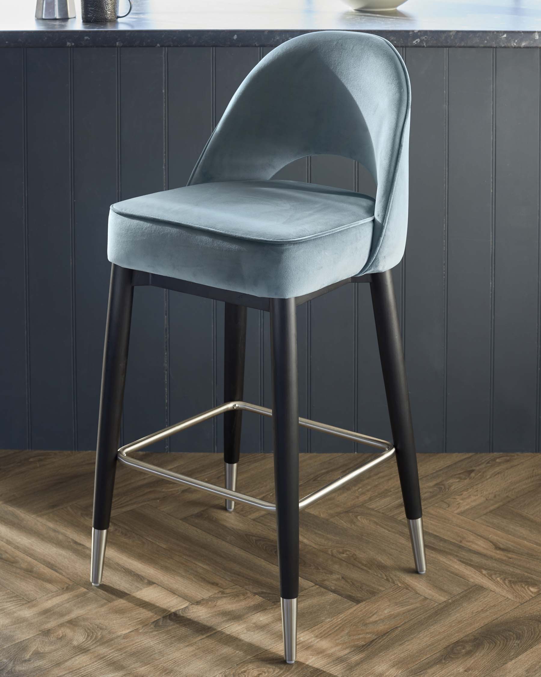 Tabouret de bar Clover en bois noir avec embouts en acier inoxydable, recouvert de velours peluche bleu-gris.
