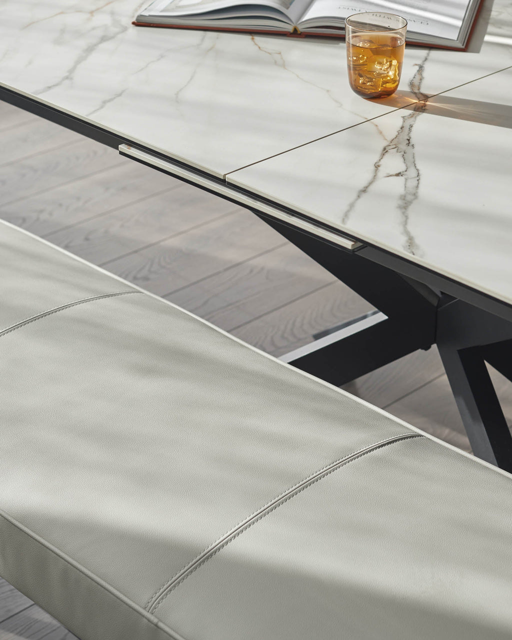 Banquette 3 places sans dossier en similicuir gris clair.