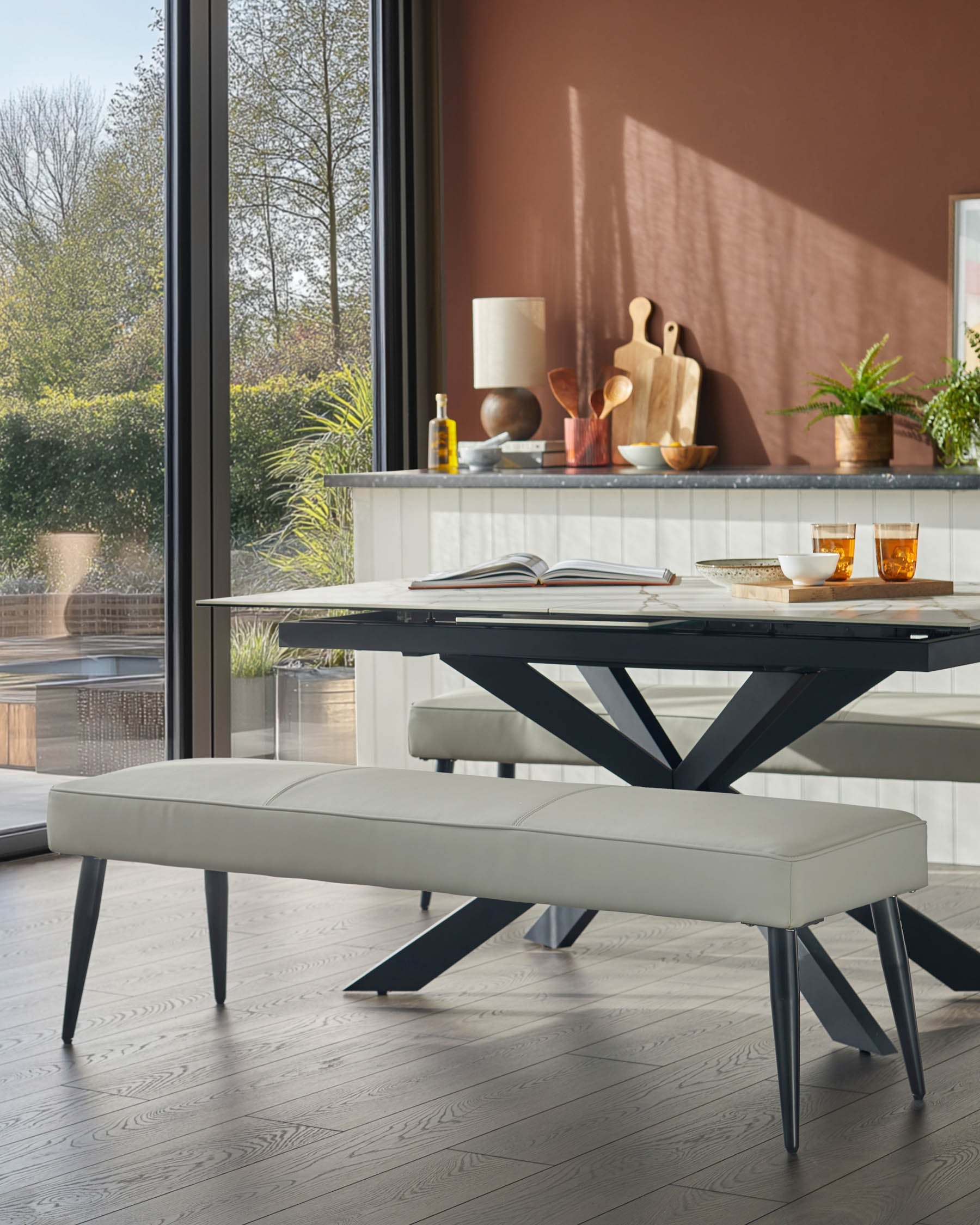 Banquette 3 places sans dossier en similicuir gris clair.