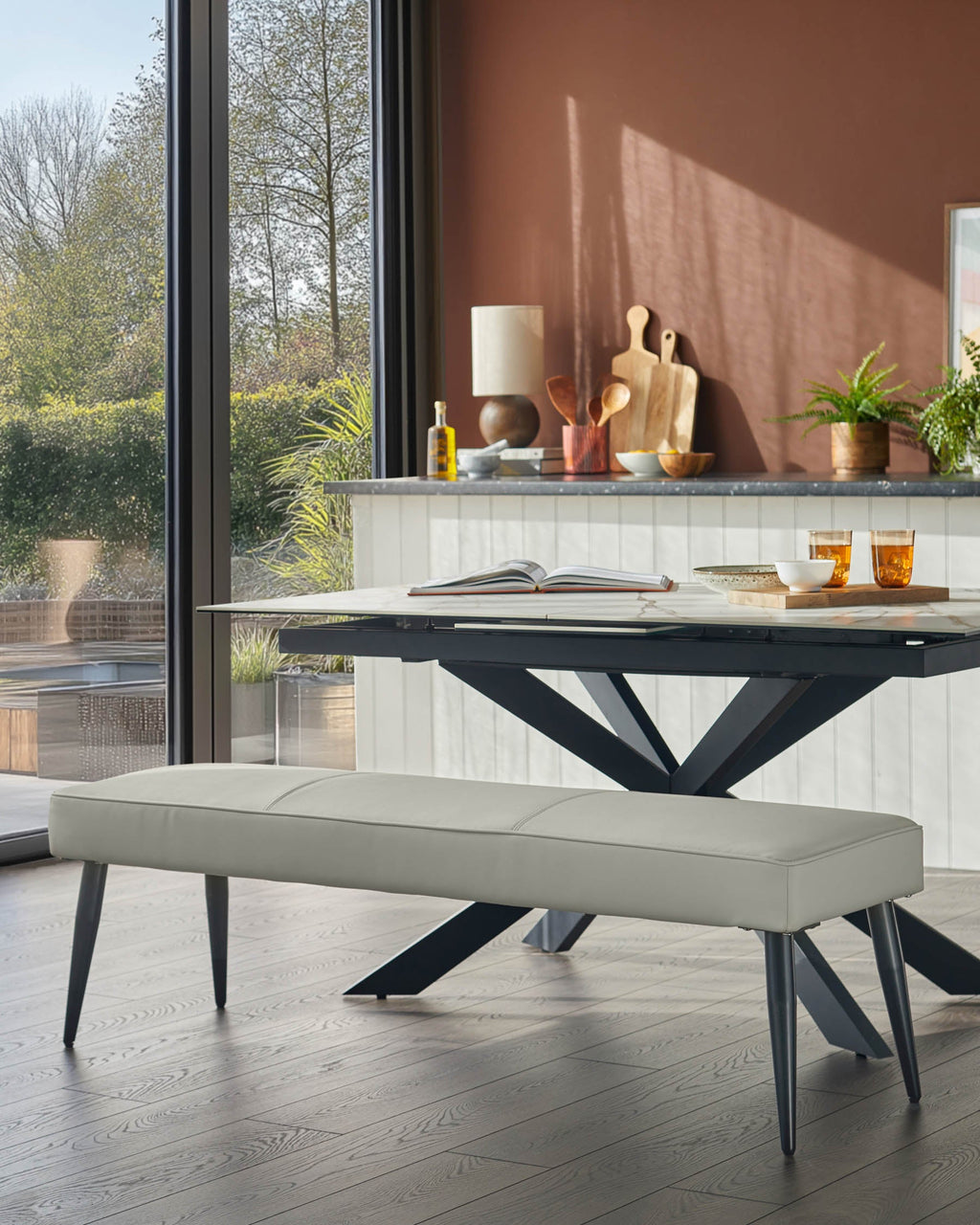 Banquette 3 places sans dossier en similicuir gris clair.